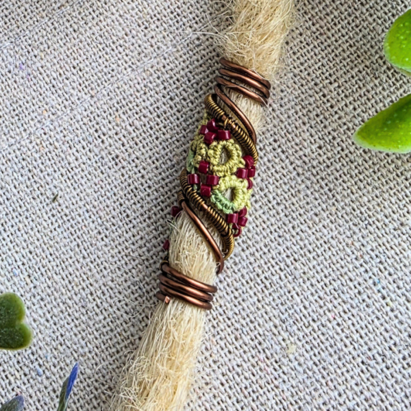 Vertikale Detailansicht der Dreadspirale Dreadsis V8 an einer Dreadlock; zeigt die stabile Wicklung aus antikbronze-farbenem Kupferdraht an den Enden des Haarschmucks.