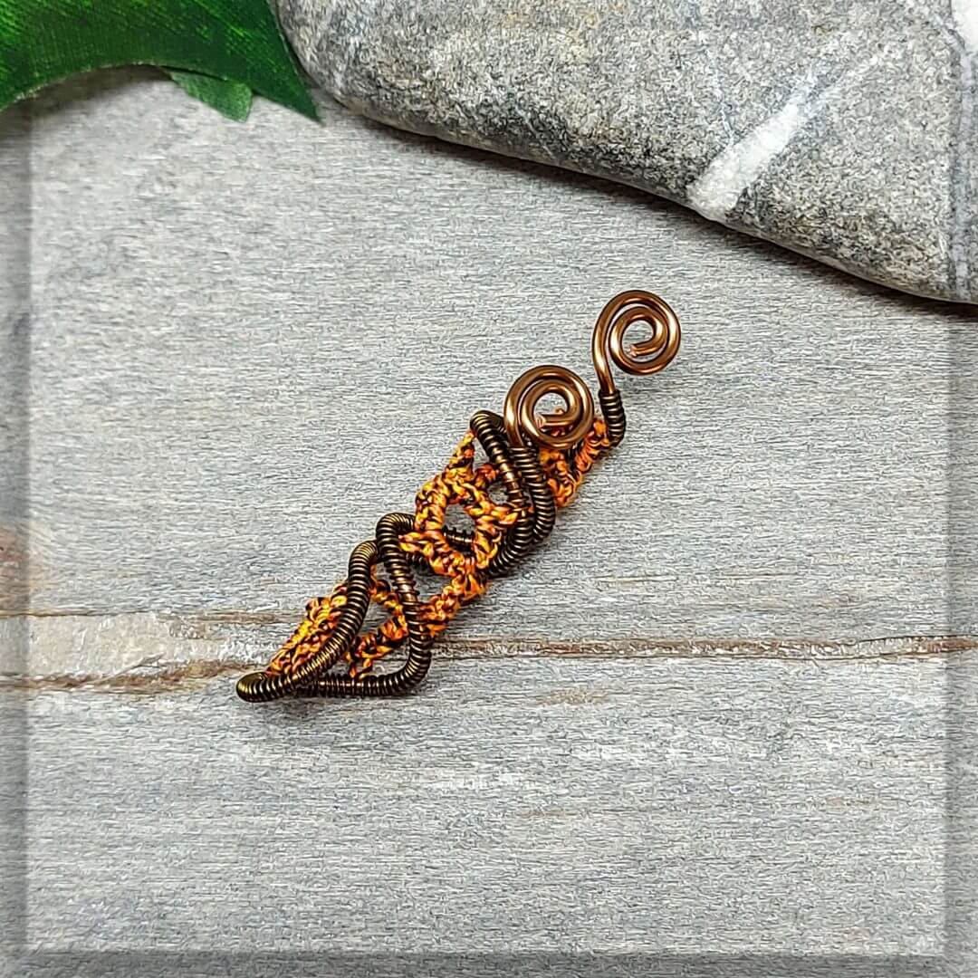 Dreadspirale in einem braun schwarz melierten Baumwollgarn geknotet und mit antikbronze Draht zu einer Spirale geformt