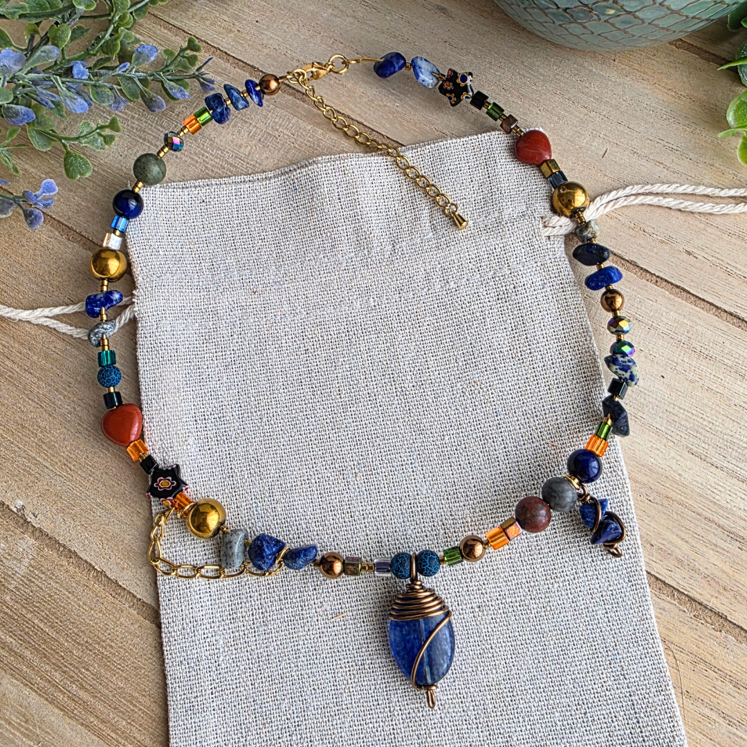 Handgefertigte Halskette mit blauem Steinanhänger, Edelsteinperlen und buntem Perlenmix in Blau, Orange und Goldtönen