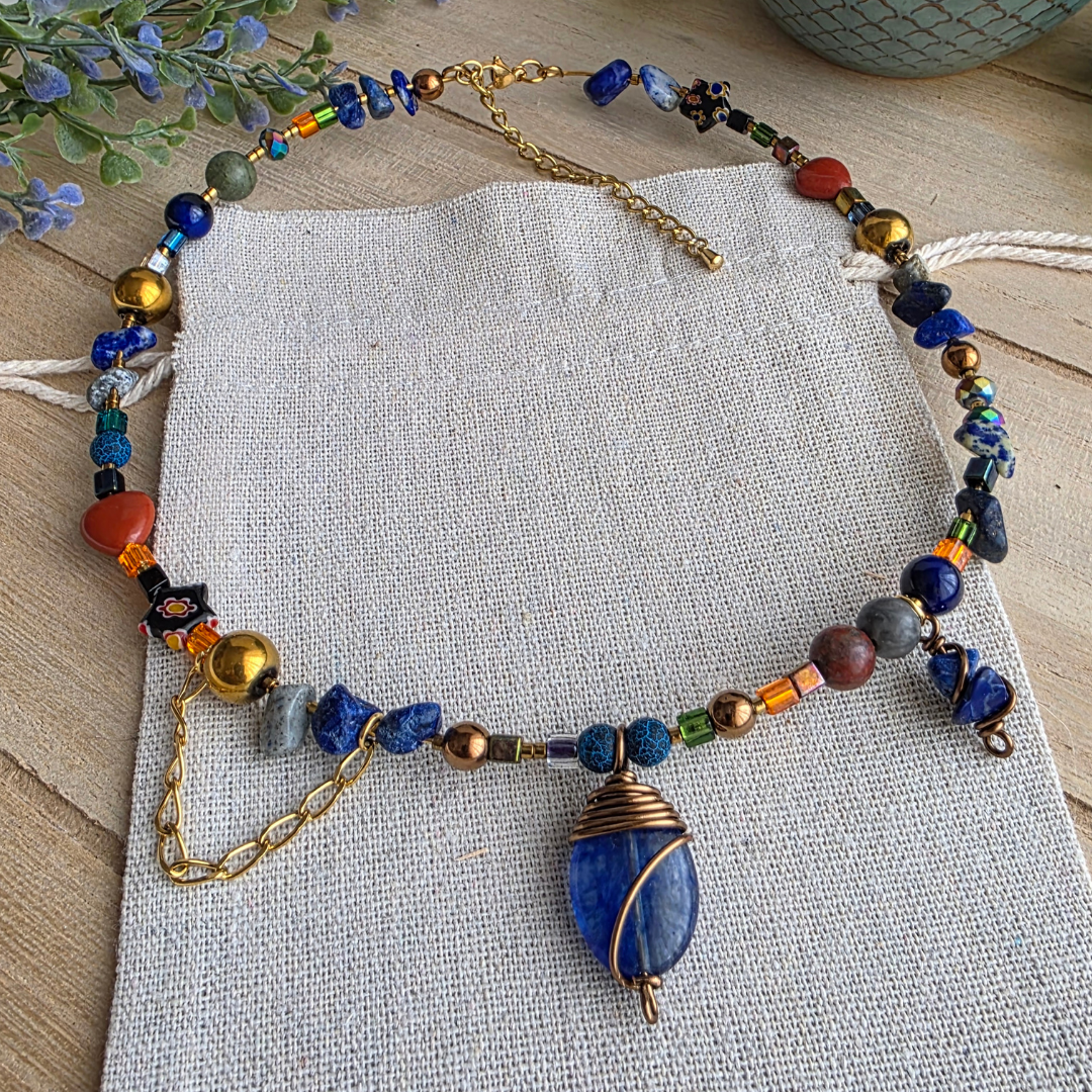 Handgefertigte Halskette mit tiefblauem Steinanhänger in bronzefarbener Drahtfassung und abwechslungsreichem Perlenmix