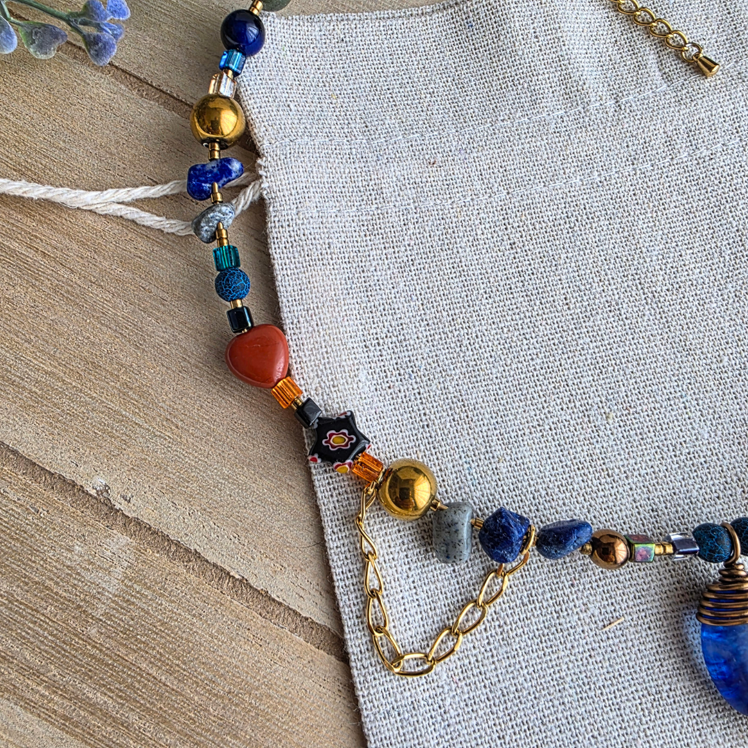 Detailansicht der Halskette mit blauen Edelsteinsplittern, orangefarbenen und goldfarbenen Perlen sowie dekorativer Kette