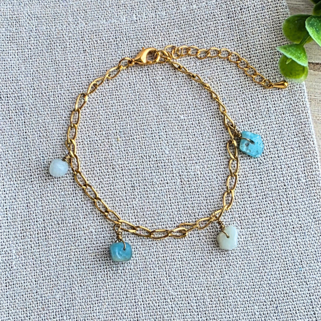 Handgefertigtes MaMari Art Armband aus 24K echtgold-vergoldetem Edelstahl mit unregelmäßigen Amazonit-Nuggets in Türkis auf hellem Leinenhintergrund.