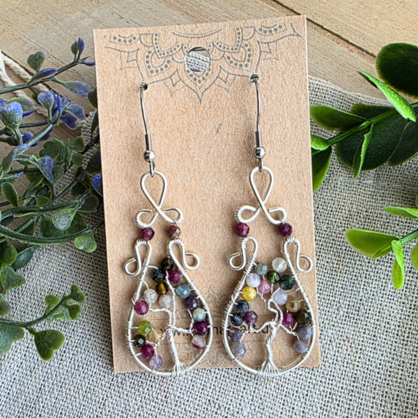 Die Ohrringe Lebensbaum Turmalin präsentiert auf einem MaMari Art Schmuckkärtchen vor Eukalyptus; zeigt die versilberten Wirework-Ohrringe mit Edelstahl-Haken.