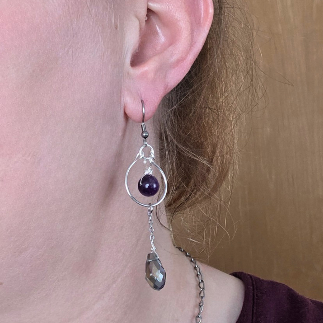 Die elfenhaften Amethyst-Ohrringe Elfenträne getragen am Ohr; zeigt die Passform, die Länge von ca. 7 cm und wie die facettierten Tropfen fallen.