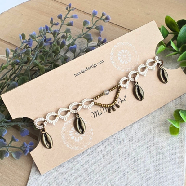 Beigefarbenes Boho-Fußkettchen auf einem Schmuckkärtchen von MaMari Art, umgeben von Dekopflanzen