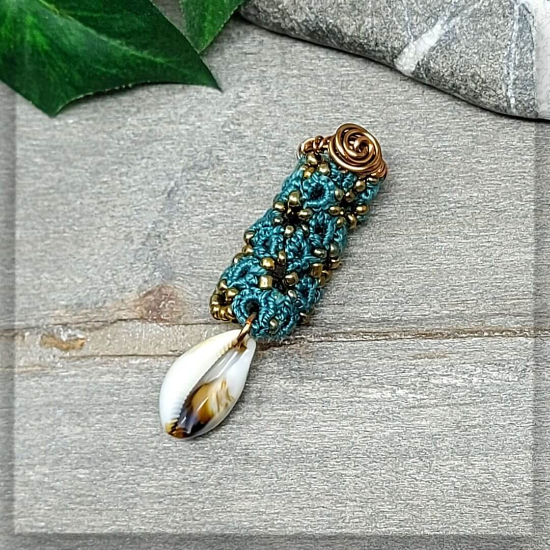 dreadschmuck in petrol mit antikbronze Glasperlen und einem Drahtrand verziert mit einer Muschel