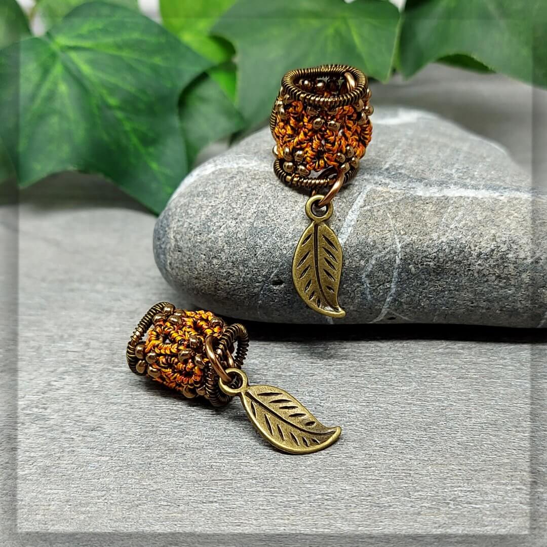 Dreadperlen geknotet aus Baumwollgarn in schwarz, orange, gelb mit antikbronze Glasperlen und Draht, mit einem Blattanhänger