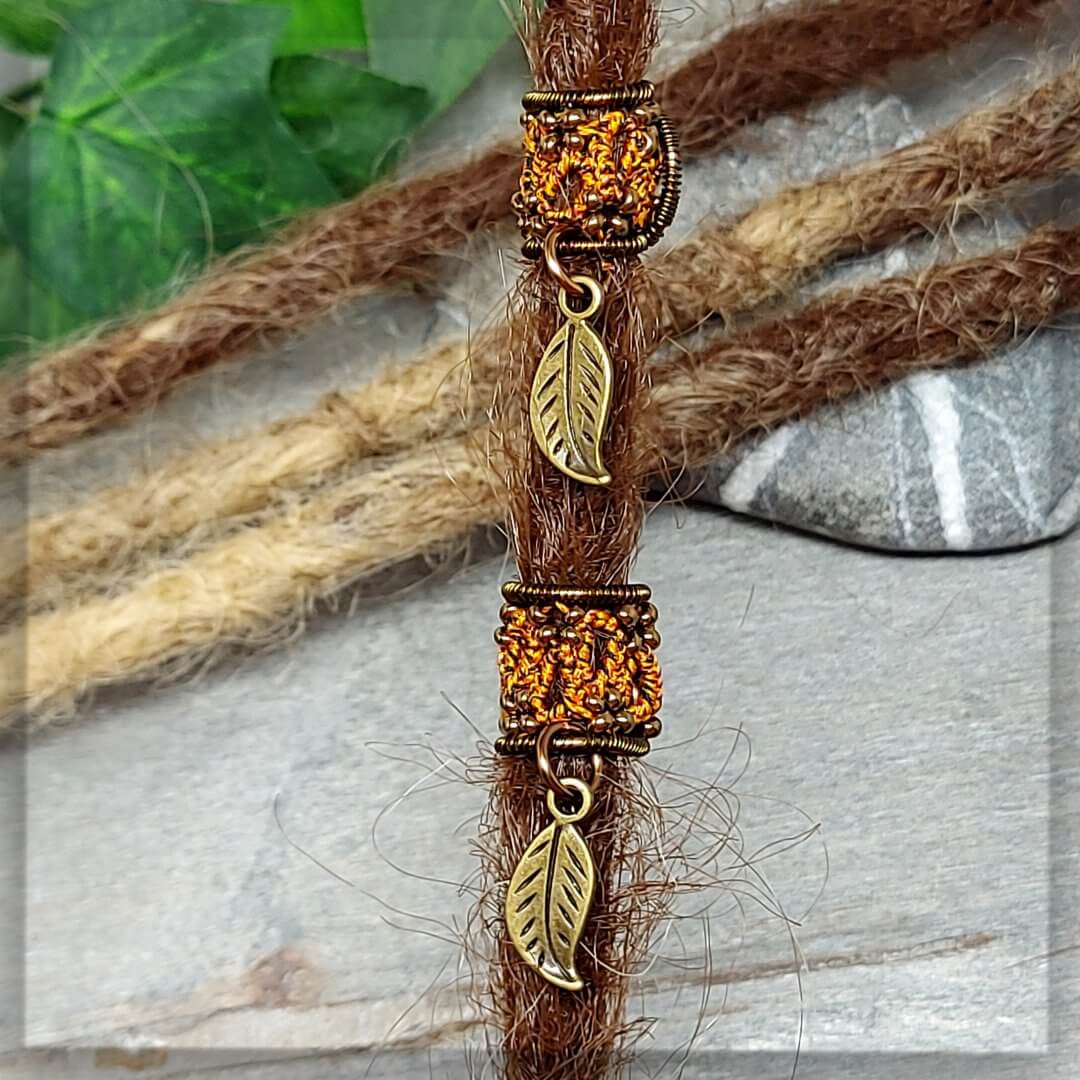 Dreadperlen geknotet aus Baumwollgarn in schwarz, orange, gelb mit antikbronze Glasperlen und Draht, mit einem Blattanhänger