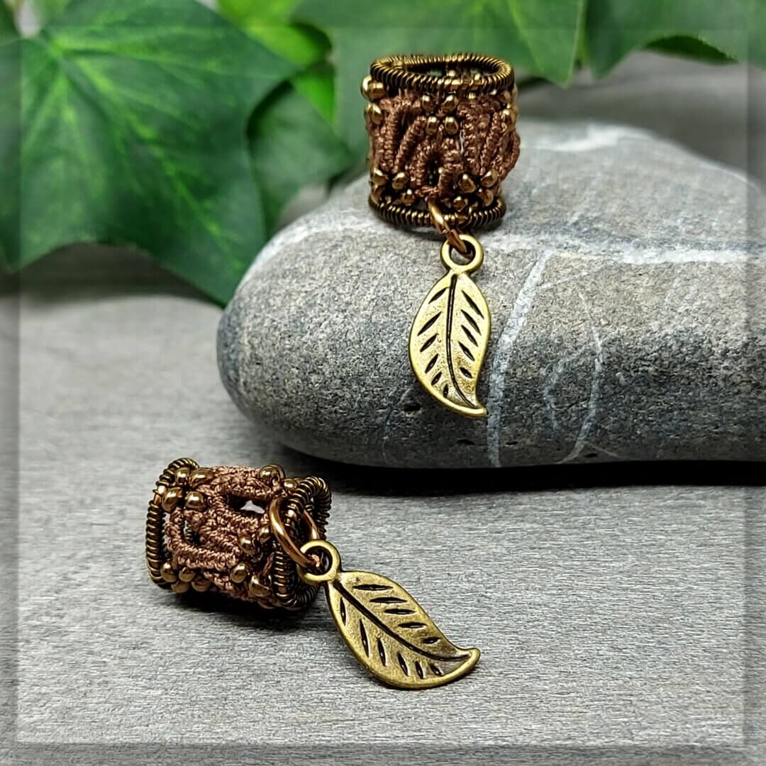 Dreadperlen aus dunkelbraunem Garn geknotet mit antikbronze Draht geformt und mit antikbronze Glasperlen sowie einem Anhänger als Blatt verziert