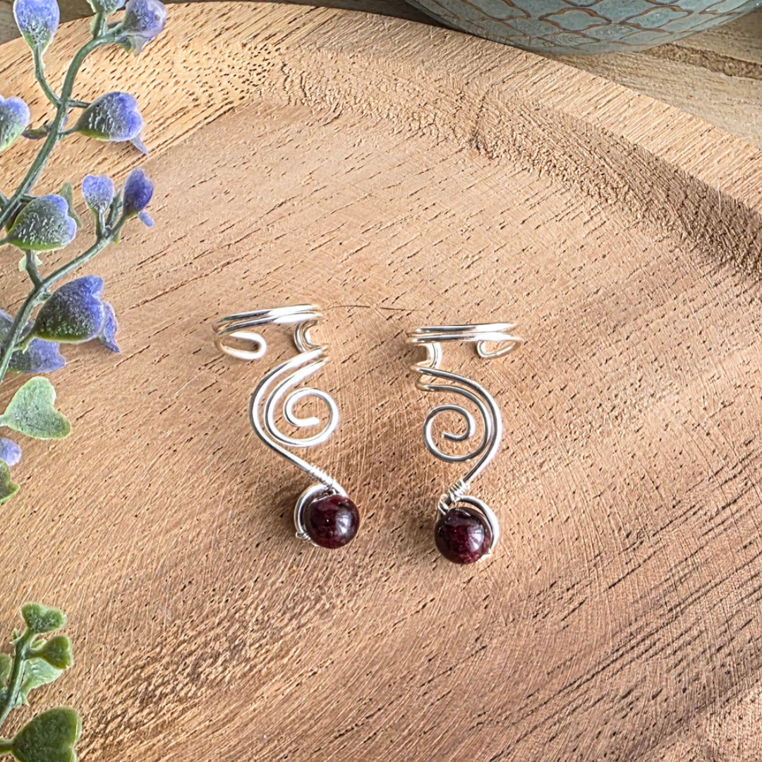 Ear Cuff Vortex Silberfarben Granat als Paar auf Holzhintergrund