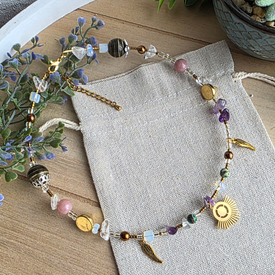 Handgefertigter Halsreif mit verschiedenen Glas- und Edelsteinperlen in Lila, Rosa, Weiß, Grün und Gold sowie goldfarbenen Flügel- und Sonnenanhängern