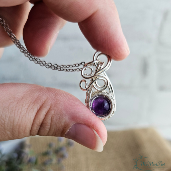 Silberne Halskette mit einem lila Amethysten filigran in silbernem Draht eingefasst. Zwischen den Finger gehalten