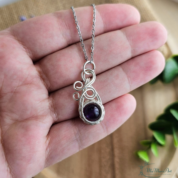 Silberne Halskette mit einem lila Amethysten filigran in silbernem Draht eingefasst. In der Hand gehalten