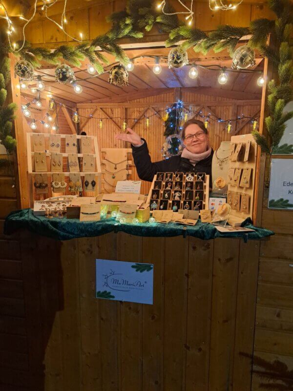 Das bin ich, Manuela von MaMari Art 2024 in einer Weihnachtsmarkt Holzhütte mit meinen ganzen Produkten die ich verkaufe. Es ist schön weihnachtlicht dekoriert und alles sinnlich beleuchtet