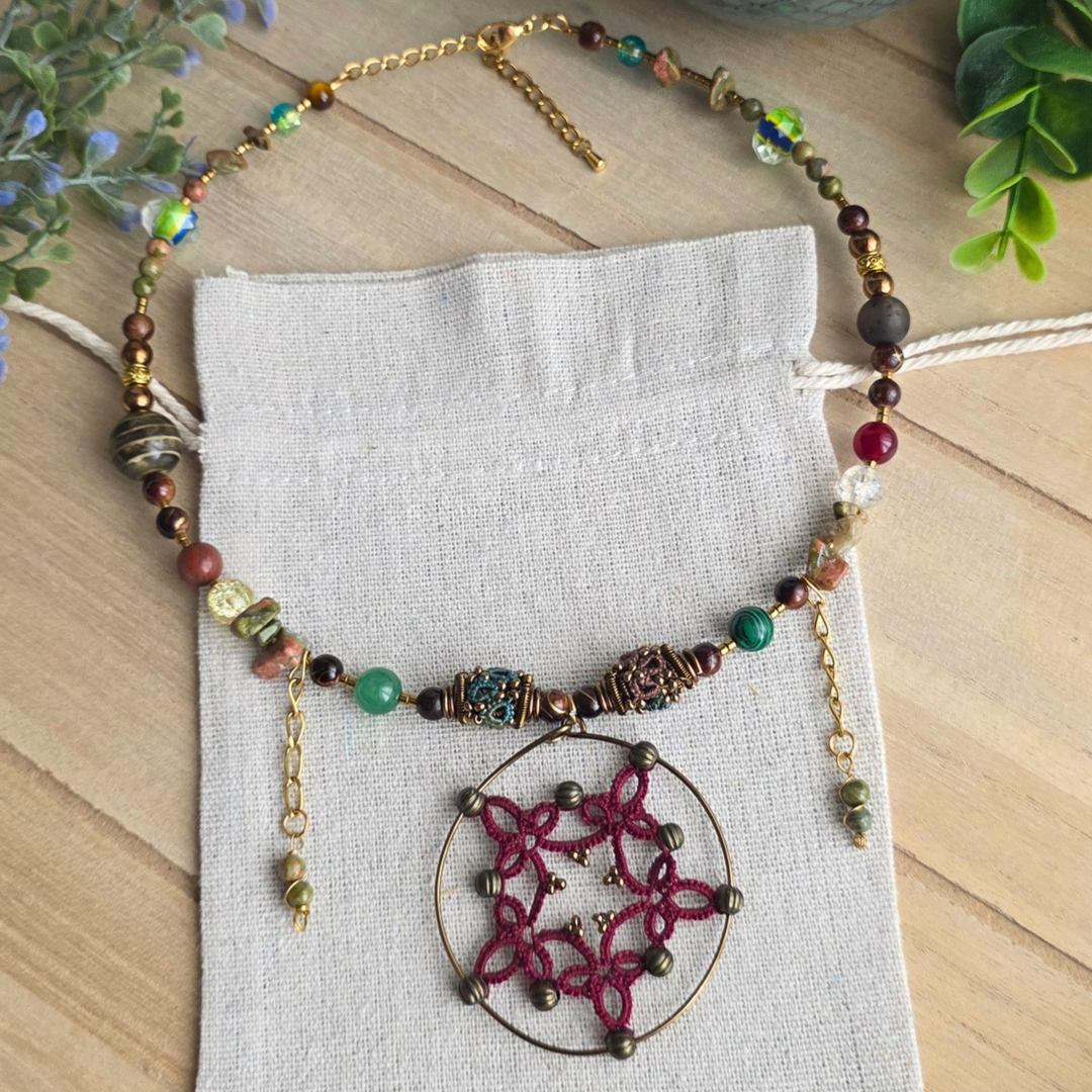 Handgefertigte Halskette im Boho-Stil mit abwechslungsreichem Perlenmix und großem kreisförmigem Anhänger mit filigraner weinroter Occhi-Spitze