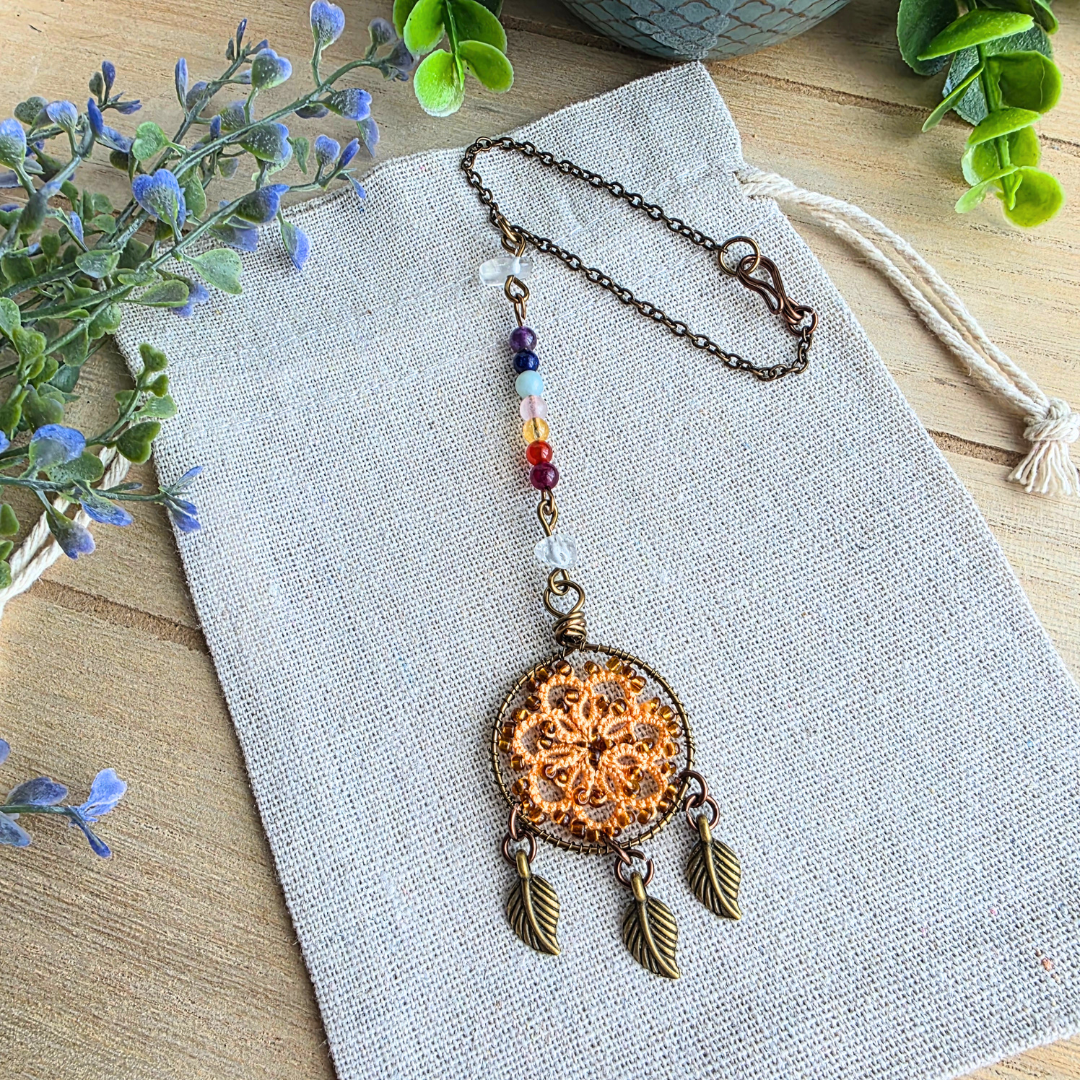 Autospiegelanhänger mit sieben Chakra-Edelsteinen, Occhi-Traumfänger in Autumn Orange, drei Blattanhängern und Befestigungskette.