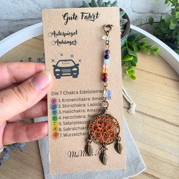 Handgefertigter Chakra Traumfänger fürs Auto in Harvest Orange mit Edelsteinreihe, Occhi-Motiv und drei Blattanhängern auf Produktkarte.