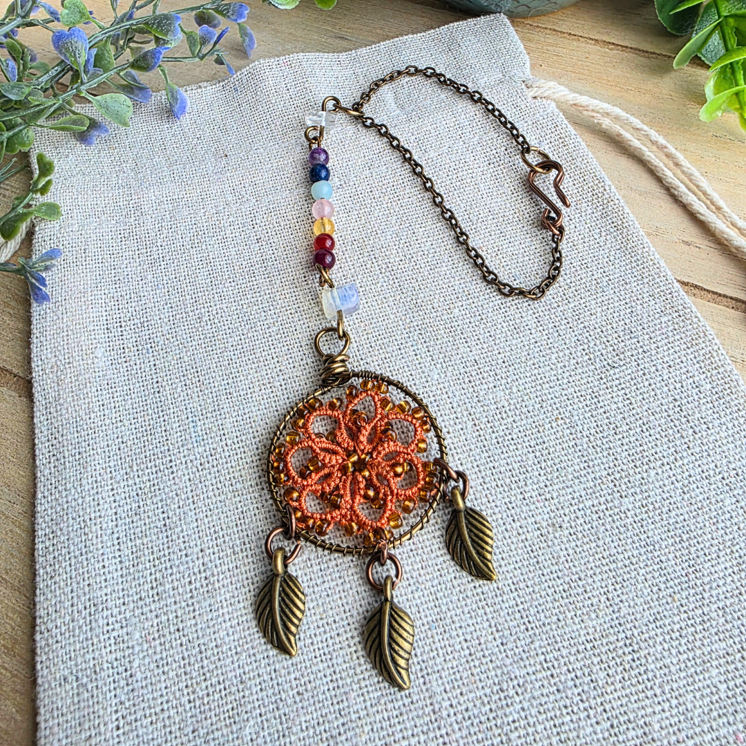 Autospiegelanhänger mit sieben Chakra-Edelsteinen, Occhi-Traumfänger in Harvest Orange, drei Blattanhängern und Befestigungskette.